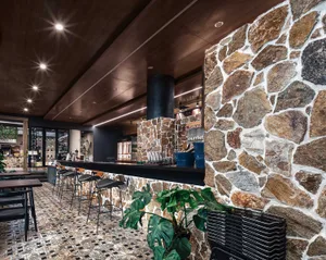 Interior of an industrial-style restaurant featuring a stone bar counter and tiled flooring.