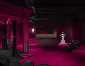 Interior of a retail space featuring black curtains, pink lighting, and velvet fabrics.
