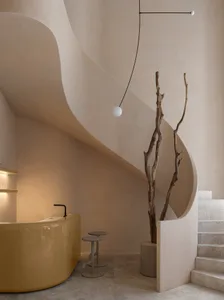 Modern minimalist interior space with concrete walls and stairs, featuring a yellow bathtub and a natural tree in a vase.