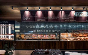 Modern food market with a wooden display featuring various types of meat and a sign indicating 'A World Gourmet Center Your F