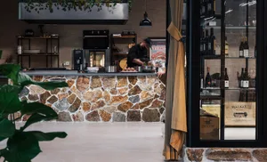 A modern restaurant with a stone countertop and a chef preparing food.