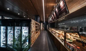 A retail grocery store with shelves displaying various products, stone accents, and a wooden ceiling and floor.