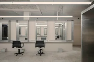 Minimalist interior design of a hair salon featuring concrete walls and mirrors.