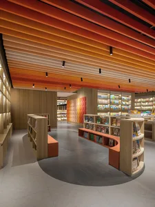 A modern minimalist bookstore interior with a curved wooden structure and colorful ceiling beams.