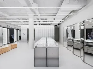 A minimalist retail shop with white metal cabinets and glass display cases showcasing modern retail designs.