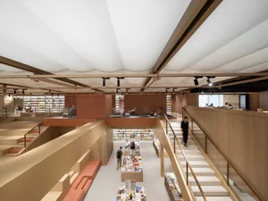 A modern library with wooden structural elements, featuring multiple levels, grand staircases, and a reading area with booksh