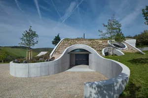Modern concrete residential building with curved entrance and greenery.
