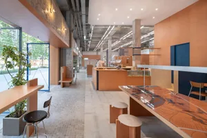 Interior of an industrial-style coffee shop featuring concrete walls, wooden tables, and glass display cases.