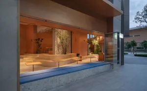 Minimalist outdoor cafe area with concrete seating and modern glass windows.