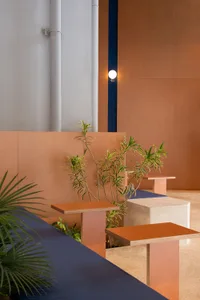 Modern cafe interior with wooden benches, cement flooring, and potted plants