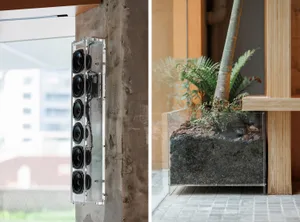 A modern interior design featuring a plexiglass audio installation mounted on a concrete wall.