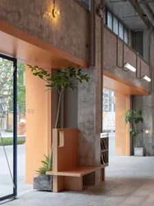 A cozy, industrial-style lobby with exposed concrete walls, plants, and warm lighting.