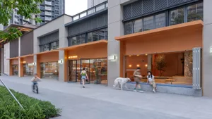 Modern storefront with concrete materials and orange awnings in an urban setting.