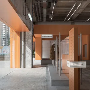 A retail clothing store interior with orange tiled walls and concrete columns