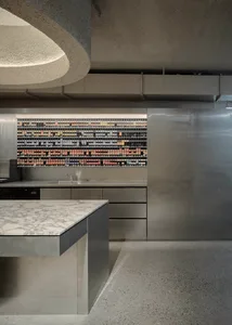 A sleek, modern commercial kitchen featuring steel appliances, marble countertops, and a minimalist design.
