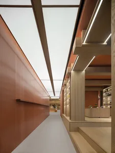 Modern minimalist retail interior featuring a perforated metal wall and wooden fixtures.