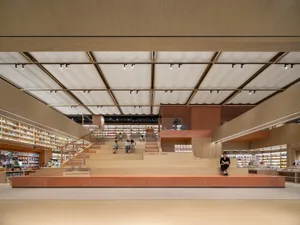 Modern library space with wooden elements and people sitting on stairs