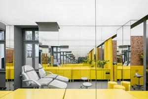 A minimalist commercial office space with yellow desks and chairs.