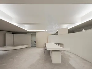 A minimalist office space featuring concrete walls and floors.