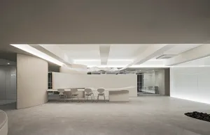 A minimalist office reception space with concrete flooring and a white reception desk.