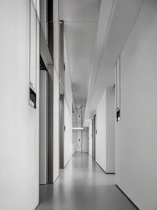 An empty minimalist white corridor with clean lines and reflections on the walls.
