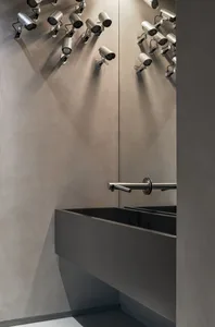 A modern bathroom with concrete walls, a sink, and numerous surveillance cameras on the walls.