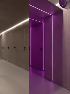 Modern office corridor with minimalist design featuring concrete walls and purple LED lighting.