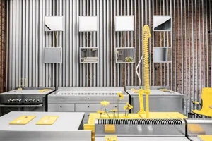 A modern industrial kitchen featuring steel countertops and a yellow faucet.