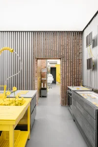A modern kitchen with grey concrete walls and yellow countertops.