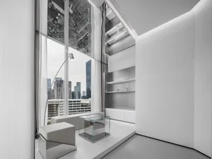 Modern living room with floor-to-ceiling glass windows, white leather furniture, and minimalist decor.