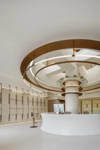 A modern lobby features dreamy white materials with circular elements and a sleek, white reception desk.