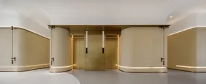 Modern lobby with gold metallic elevator paneling and curved walls