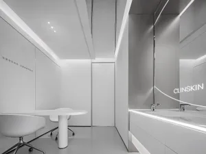Modern office space with minimalistic design, featuring sleek white furniture and a white podium with a chair.