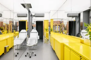 Bright yellow furniture and white chairs in a modern hair salon interior