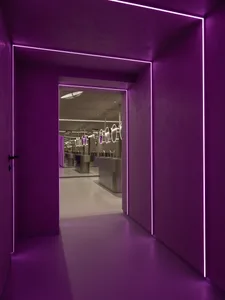A modern lavatory interior with purple ambient lighting.