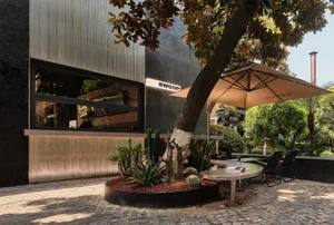 Outdoor seating area with metal cladding walls, brick paving, and glass doors at a minimalist cafe.