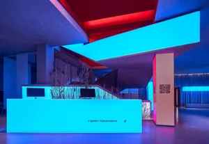A modern, industrial-style cinema lobby with concrete walls and a blue light installation.