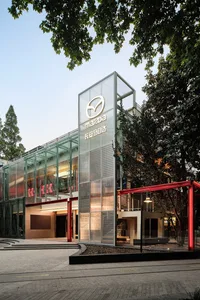Modern commercial building constructed with glass and aluminum materials, featuring a distinct geometric design.