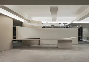 A modern corporate reception area with curved concrete surfaces and white lighting.