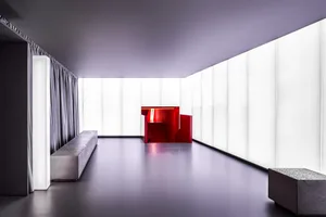 Modern entryway featuring sleek, minimalist design with red accents on staircase and walls, complemented by concrete flooring
