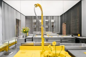 A modern kitchen with yellow tiles, stainless steel appliances, and a white countertop.