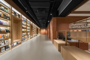 A modern library with wooden shelves, illuminated by LED lights, featuring a mix of books and magazines, and a seating area w