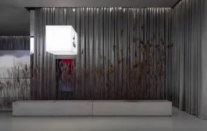 Modern living room featuring concrete furniture, curtains adorned with reeds, and illuminated lighting.