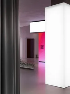 Modern minimalist hallway with a bright white lighted column and a pink-lit room in the distance.