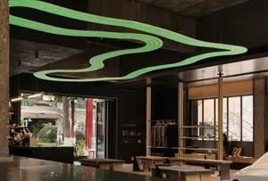 A modern retail storefront with concrete walls and illuminated green lights hanging from the ceiling