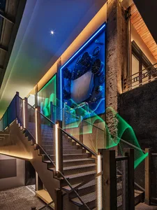 A modern staircase featuring glass, metal, and concrete materials with illuminated steps and handrails.
