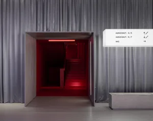 An interior design image showing a staircase in a cinema hall with a red interior and concrete walls.