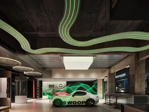 Modern automotive dealership with concrete walls, green neon lights, and a white car with green light effects.