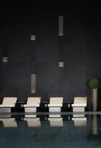 A modern poolside lounge featuring concrete seating and lighting.