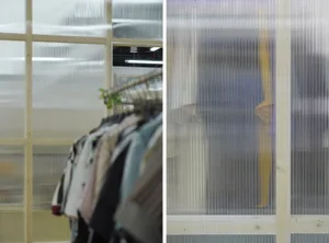 A row of clothing hanging on a transparent plastic clothing rack.